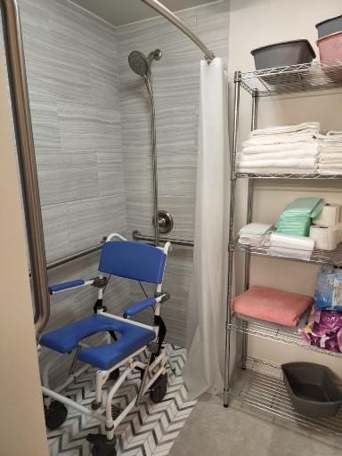 A living room with a TV displaying Hillsong Worship, a wall clock, a black shelf with decor items, a horse painting, leather furniture, and wood flooring.